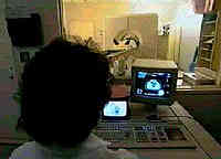 frame from video showing man in background getting radiation while a technician in the foreground is monitoring the process on a computer screen